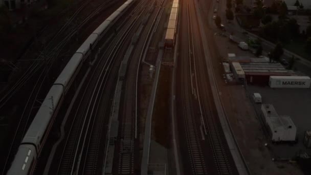 AERIAL: Vuelo sobre Berlín, Alemania Estación Central de Ostbahnhof con ICE Tren conduciendo al atardecer, la luz del sol y la vista sobre Alexanderplatz TV Tower, Sunflairs — Vídeos de Stock