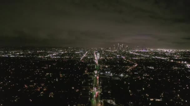 AERIAL: Uitzicht over Los Angeles 's nachts met Wilshire Boulevard Glow Streets en City Car Traffic Lights — Stockvideo
