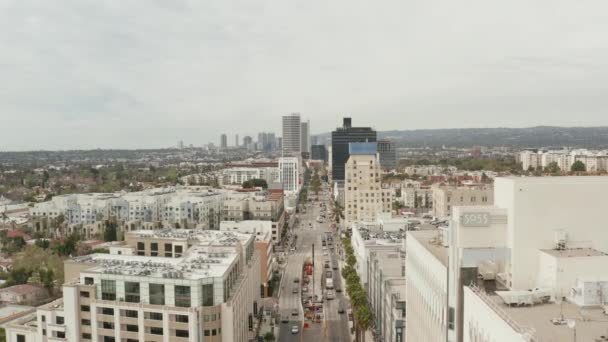 AERIAL: Flyg över Wilshire Boulevard nära Street och byggnader med biltrafik i Los Angeles, Kalifornien på Overcast Day — Stockvideo