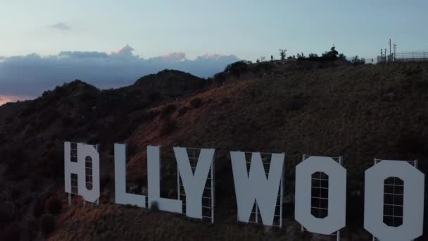 AERIAL: Repülés Hollywood Sign felett, Hollywood Hills kilátással a völgyre, Burbank gyönyörű naplementével és felhőkkel — Stock videók