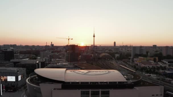 AERIAL: Vuelo sobre Berlín, Alemania en la hermosa puesta del sol, la luz del sol y la vista en Alexanderplatz TV Tower y Ostbahnhof y Mercedes Benz Arena, Sunflairs — Vídeo de stock