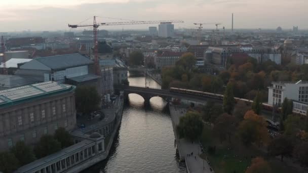 AERIAL: над мостом Берліна (Німеччина) річка в центрі осінніх кольорів у напрямку Берліна Фрідріхштрасса на прекрасному Сансет. — стокове відео