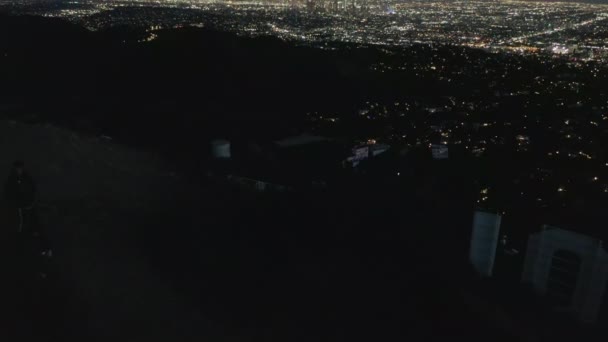 AERIAL: Spectacular Flight Close over Hollywood Sign Letter at Night with Los Angeles Cscape Lights — 图库视频影像