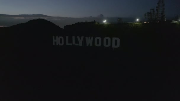 AERIAL:ハリウッドサイン、ハリウッドヒルズの上空を夜に飛行し、バレー、バーバンク、シティライトを眺めます — ストック動画