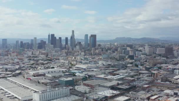 AERIAL: Langsame Seitenaufnahme der Skyline von Downtown Los Angeles mit Lagerhauskunst im Vordergrund mit blauem Himmel und Wolken — Stockvideo