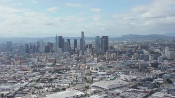 AERIAL: Langsame Seitenaufnahme der Skyline von Downtown Los Angeles mit Lagerhauskunst im Vordergrund mit blauem Himmel und Wolken — Stockvideo