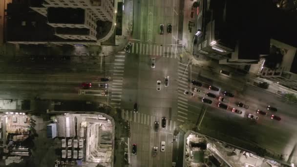 AERIAL: Aumento de la sobrecarga en la calle de la intersección con el sitio grande de la construcción y agujeros en tierra en la noche con las calles que brillan y los semáforos del coche de la ciudad — Vídeos de Stock