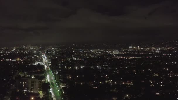 AERIAL: Over Dark Hollywood Los Angeles at Night view on Wilshire Blvd with Clouds over Downtown and City Lights — Stock Video