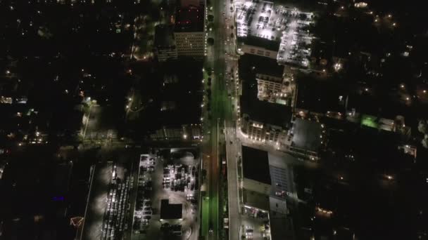 AERIAL: Consulta sobre Wilshire Boulevard Street en Hollywood Los Ángeles por la noche con vista al centro y las calles brillantes y los semáforos de coches urbanos — Vídeo de stock