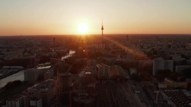 AERIAL:美しい夕日、日光でドイツのベルリン上空を飛行し、 Alexanderplatz TV TowerとOstbahnhof 、 Sunflairsで見る — ストック動画