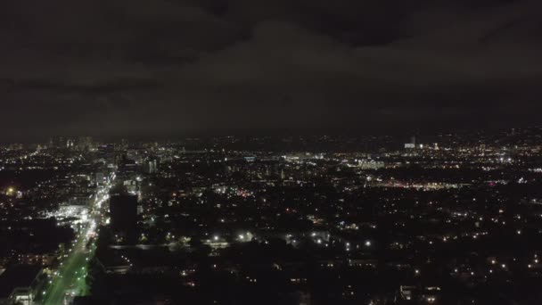 AERIAL: Over Dark Hollywood Los Angeles at Night view on Wilshire Blvd with Clouds over Downtown and City Lights — Stock Video