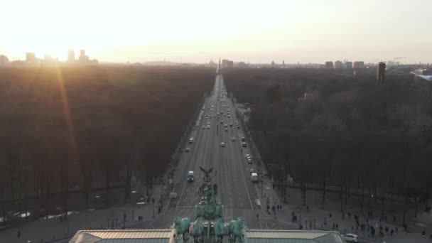 AERIAL: Über Straße und Tiergarten des 17. Juni mit Berliner Siegessäule, die das Brandenburger Tor im wunderschönen Sonnenuntergang erstrahlen lässt — Stockvideo
