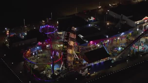 АЭРИАЛ: захватывающий вид на Санта-Монику Пир ночью с Колесом обозрения и цветными огнями , — стоковое видео
