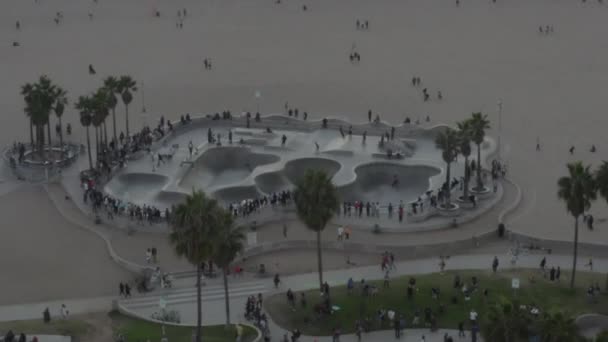 AERIAL: Odlot z Venice Beach Skatepark z Przybyszami i Palmami, Zachód słońca w Los Angeles — Wideo stockowe