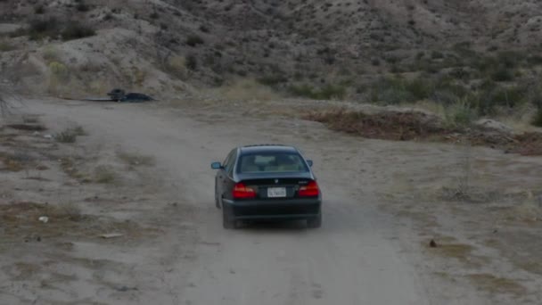 AERIAL: Följ skott av svart bil körning tråg öken i Kalifornien, dagsljus — Stockvideo