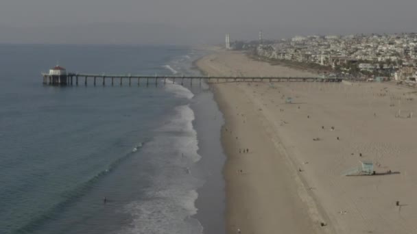 AERIAL: Gente en las olas de la playa, agua con muelle en Los Ángeles, California, soleado, cielo azul — Vídeo de stock