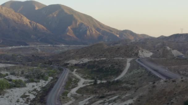 AERIAL: Över Kalifornien Country Side med motorväg och berg vid solnedgången — Stockvideo