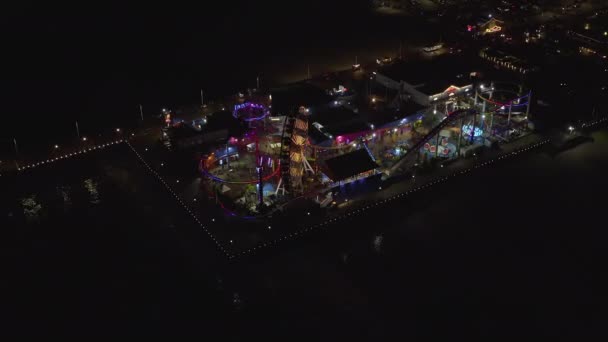 AERIAL: Widok na molo w Santa Monica nocą z diabelskim młynem i kolorowymi światłami, — Wideo stockowe