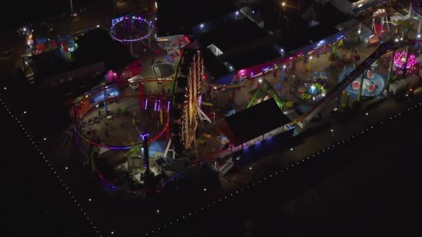 AERIAL: Beathtaking view on Santa Monica Pier at night with Ferris Wheel and colorful lights, — 图库视频影像