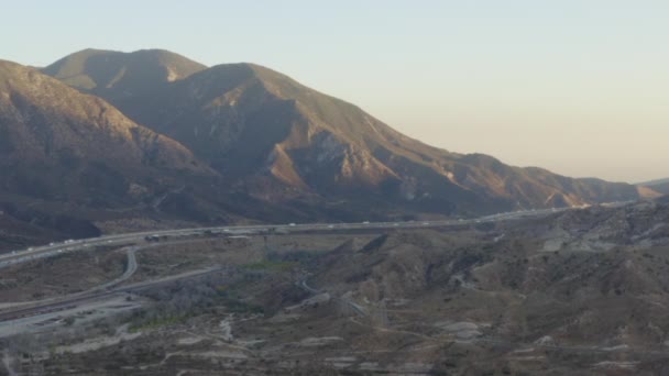 AERIAL: Over California Country Side met snelweg en bergen bij zonsondergang — Stockvideo