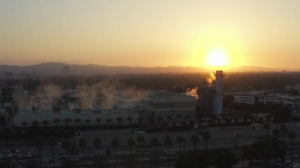 AERIAL: Stoomfabriek met palmbomen en drukke snelweg in Burbank, Los Angeles, Californië, Zonsondergang — Stockvideo