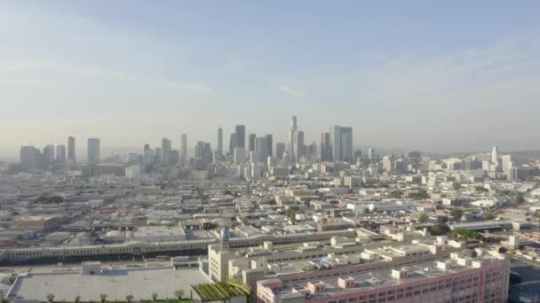 AERIAL: Zapierające dech w piersiach szerokie ujęcie w kierunku centrum Los Angeles, California Skyline w pięknym słońcu, błękitne niebo, — Wideo stockowe