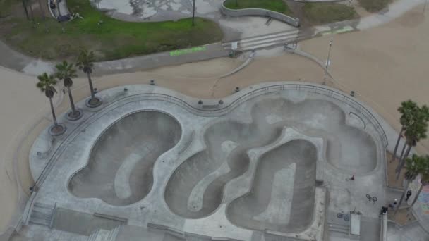 AERIAL: Cerrado en el parque acuático Venice Beach Skatepark vacío por la mañana, Cloudy Los Angeles, California. — Vídeo de stock