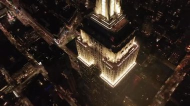 Gökyüzündeki ikonik Empire State binası üzerinde nefes kesici bir çember oluşturarak paralel caddeler ve kavşakları aydınlattı Manhattan, New York 'ta gece yarısı konutlar ve ofis binaları.
