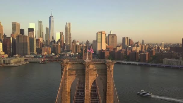 AERIAL: Flyg över Brooklyn Bridge med amerikanska flaggan viftande och East River utsikt över Manhattan New York City Skyline i vackra — Stockvideo