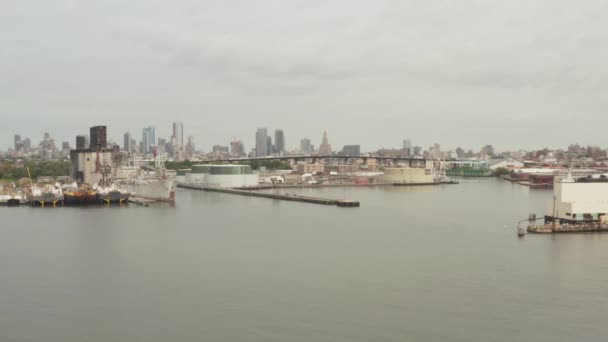 AERIAL: Verso Manhattan, New York City Skyline con banchine e barche da carico in una giornata grigia nuvolosa — Video Stock