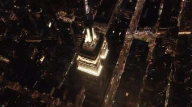 Gökyüzündeki ikonik Empire State binası üzerinde nefes kesici bir çember oluşturarak paralel caddeler ve kavşakları aydınlattı Manhattan, New York 'ta gece yarısı konutlar ve ofis binaları.