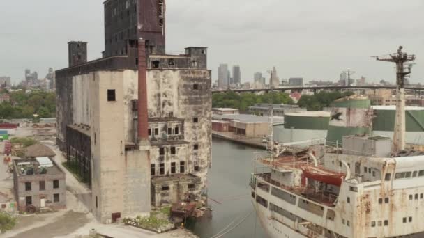 AERIAL: Sobre Rusty velhos navios de carga e armazém velho nas docas de Nova York em um dia cinzento nublado — Vídeo de Stock