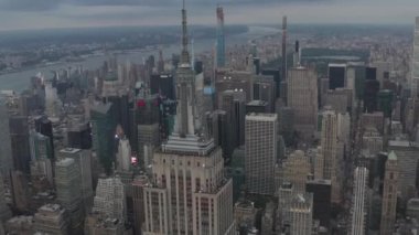 Manhattan 'daki Empire State binasının üzerinde bulutlu bir günde kalabalık şehirde tırpanlarla çevrili destansı bir manzara var. 