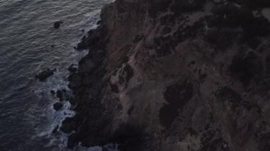 Malibu, California 'da sahil şeridi manzaralı Paficic Okyanusu üzerinde gün batımında dağ yamacıyla uçmak