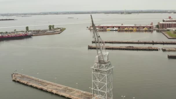 AERIAL: Guindaste industrial circulante em docas da cidade de Nova York com barcos e rio — Vídeo de Stock