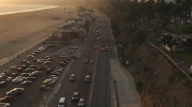 Los Angeles, Santa Monica İskelesi 'nin yanındaki Pasifik Sahil Otobanı manzaralı gün batımı dalgalarında hafif trafik ve okyanus manzaralı. 