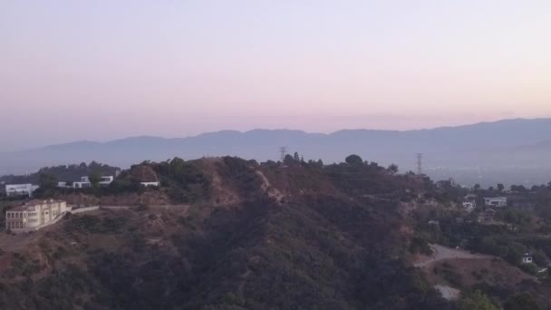 AERIAL: Sobre Hollywood Hills al amanecer con vista a las colinas y el valle en Los Ángeles vista — Vídeos de Stock
