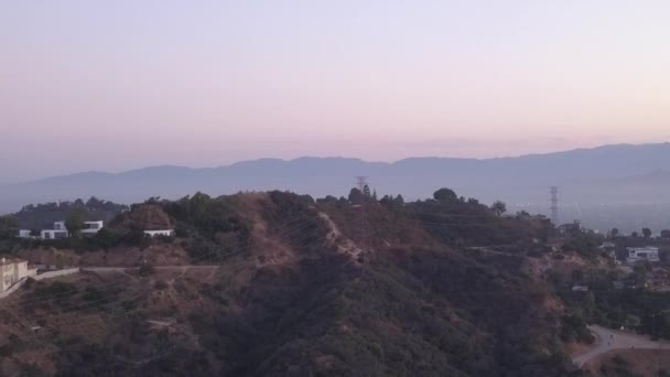 AERIAL: Sobre Hollywood Hills al amanecer con vista a las colinas y el valle en Los Ángeles vista — Vídeos de Stock