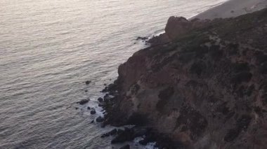 Malibu, California 'da sahil şeridi manzaralı Paficic Okyanusu üzerinde gün batımında dağ yamacıyla uçmak