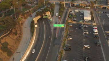 Santa Monica İskelesi, Los Angeles otoparkı üzerinde, gün batımında geçen kuşların ve trafik ışıklarının kesiştiği kıyıya doğru. 