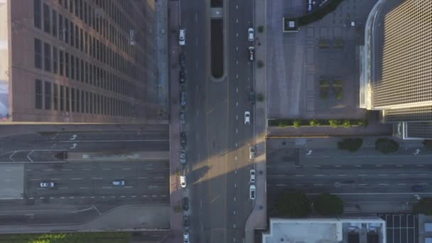 AERIAL: Slow Birds Eye超高層ビルの屋根と車の交通量が通過する景色を望む美しい日の出の光で、ロサンゼルスダウンタウンの上空のフライトを見る — ストック動画
