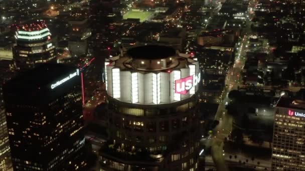 AERIAL: Vista de cerca del rascacielos US Bank Tower y el centro de Los Ángeles, California por la noche, luces brillantes de la ciudad — Vídeo de stock