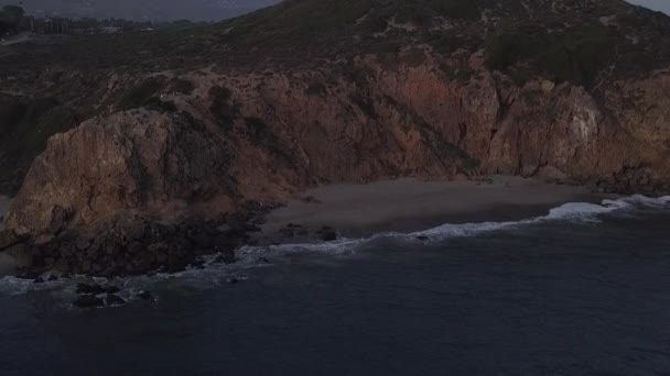 AERIAL: let nad Malibu, Kalifornie pohled na pláž Shore Line Paficic oceán při západu slunce s horským útesem — Stock video