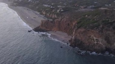 Malibu, California 'da sahil şeridi manzaralı Paficic Okyanusu üzerinde gün batımında dağ yamacıyla uçmak