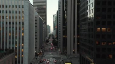 Los Angeles şehir merkezinde gün batımında trafik ışıklarıyla birlikte gökdelen kanyonu boyunca destansı bir uçuş. 