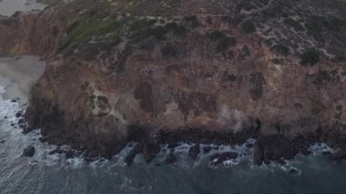 Malibu, California 'da sahil şeridi manzaralı Paficic Okyanusu üzerinde gün batımında dağ yamacıyla uçmak