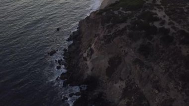 Malibu, California 'da sahil şeridi manzaralı Paficic Okyanusu üzerinde gün batımında dağ yamacıyla uçmak