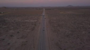Loneley üzerinde terk edilmiş çöl yolu üzerinde kırmızı bir araba ile uçuyor. 