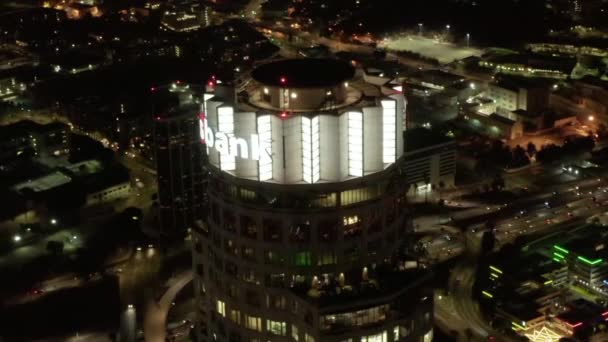 AERIAL: Närbild av US Bank Tower skyskrapa och Downtown Los Angeles, Kalifornien på natten, glödande stadsljus — Stockvideo
