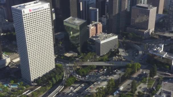 AERIAL: Vista de aves del centro de Los Ángeles, California tráfico de intersección con palmeras y cielo azul Skyline y día soleado — Vídeo de stock